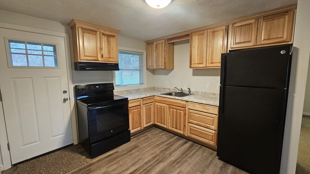 a kitchen with granite countertop a refrigerator stove top oven and sink