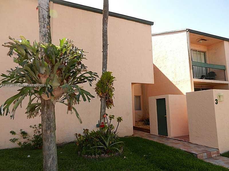 a palm tree sitting in front of a house with potted plants