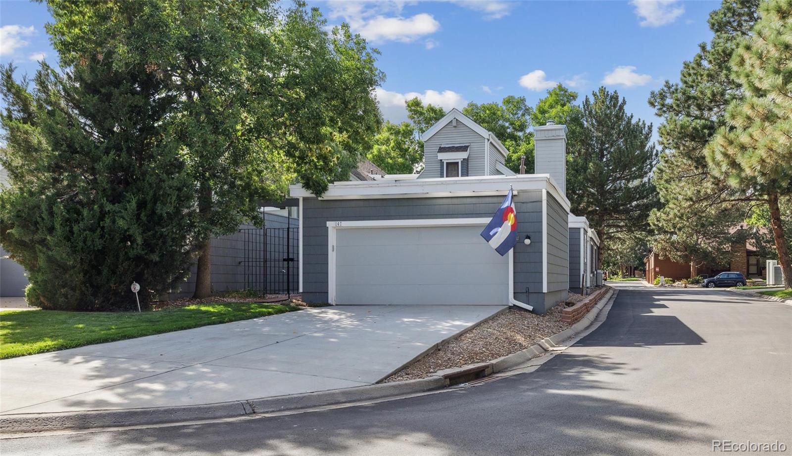 a small white house with a white fence next to a road