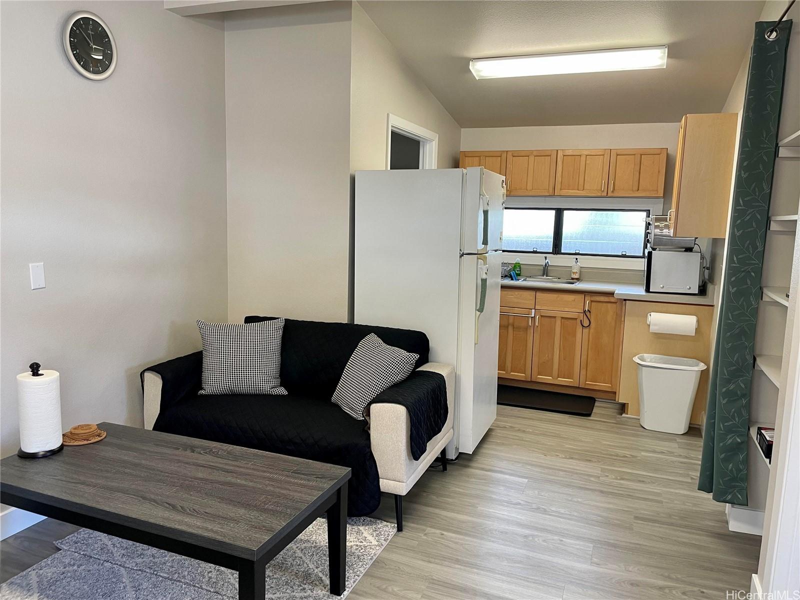 a living room with stainless steel appliances furniture a rug and a wooden floor