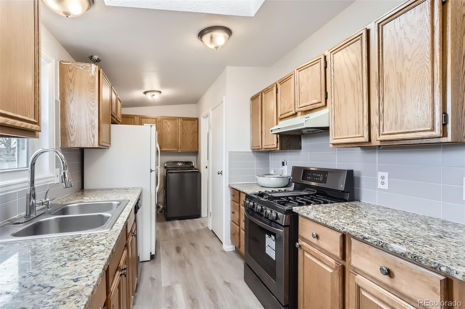 a kitchen with stainless steel appliances granite countertop a sink stove and refrigerator