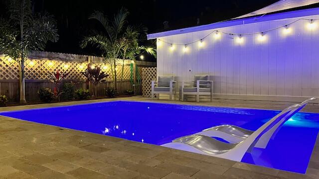 a view of swimming pool with a red chairs in front of house