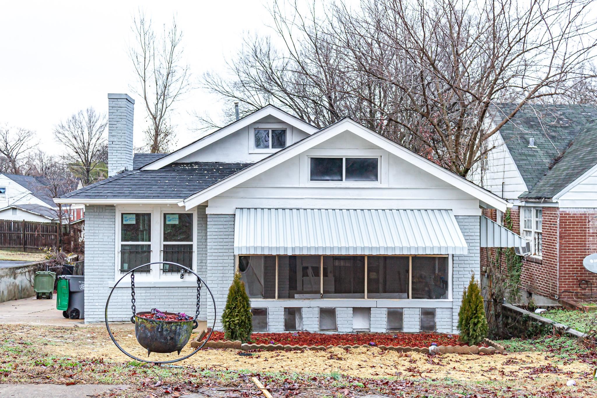 a front view of a house with a yard and potted plants