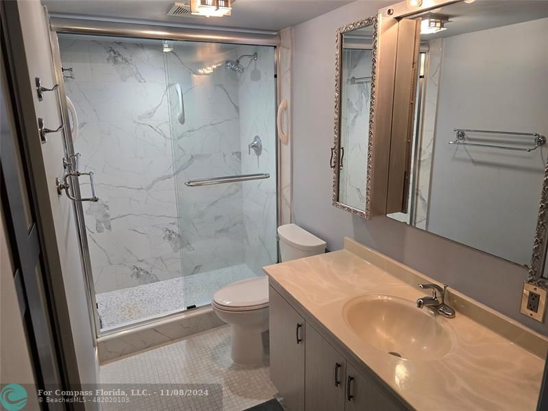 a bathroom with a granite countertop sink toilet and shower