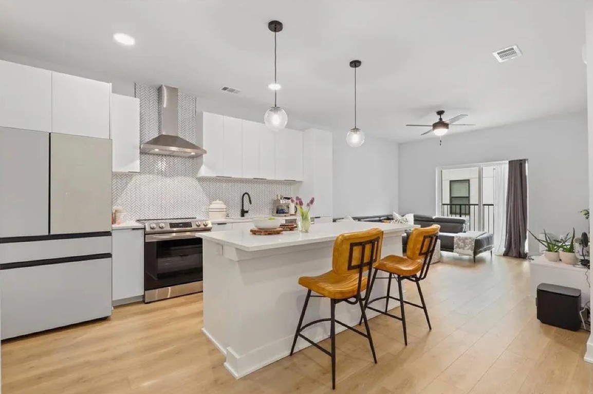 a kitchen with stainless steel appliances kitchen island a table chairs and a refrigerator