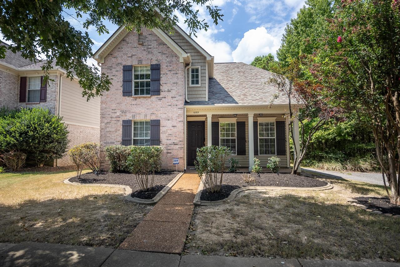 a front view of a house with a yard and potted plants