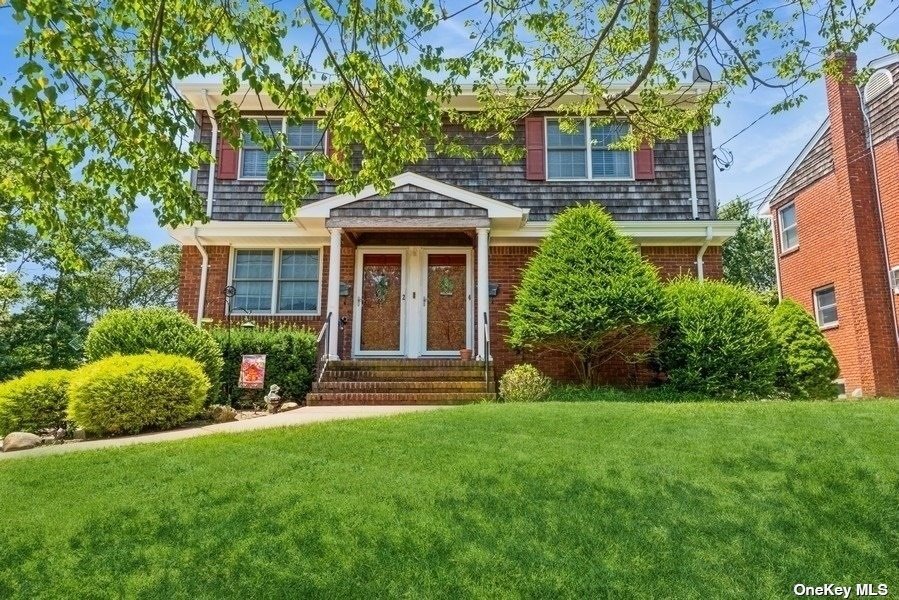 a front view of a house with a yard and trees