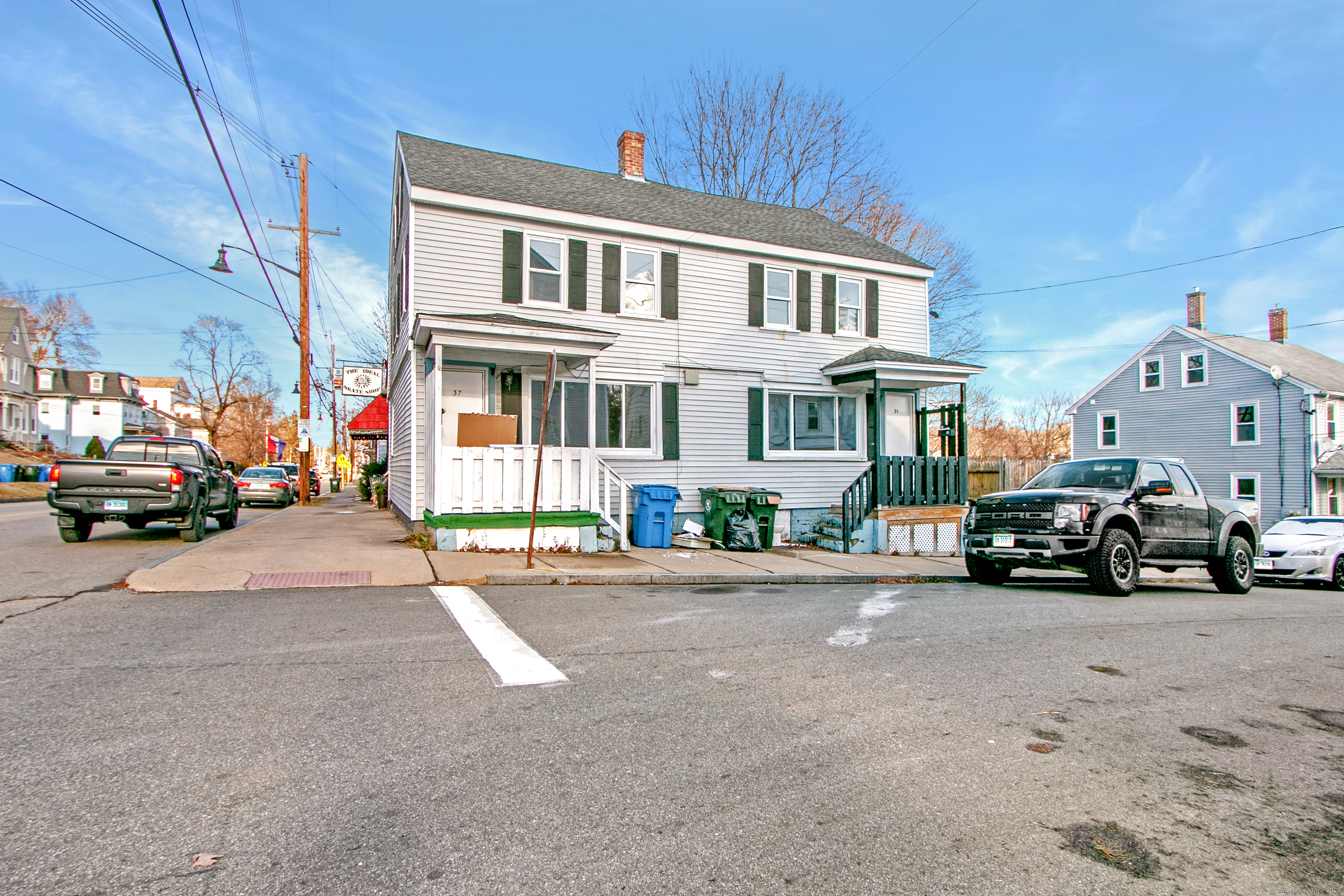 a view of road with card parked on side and retail shops