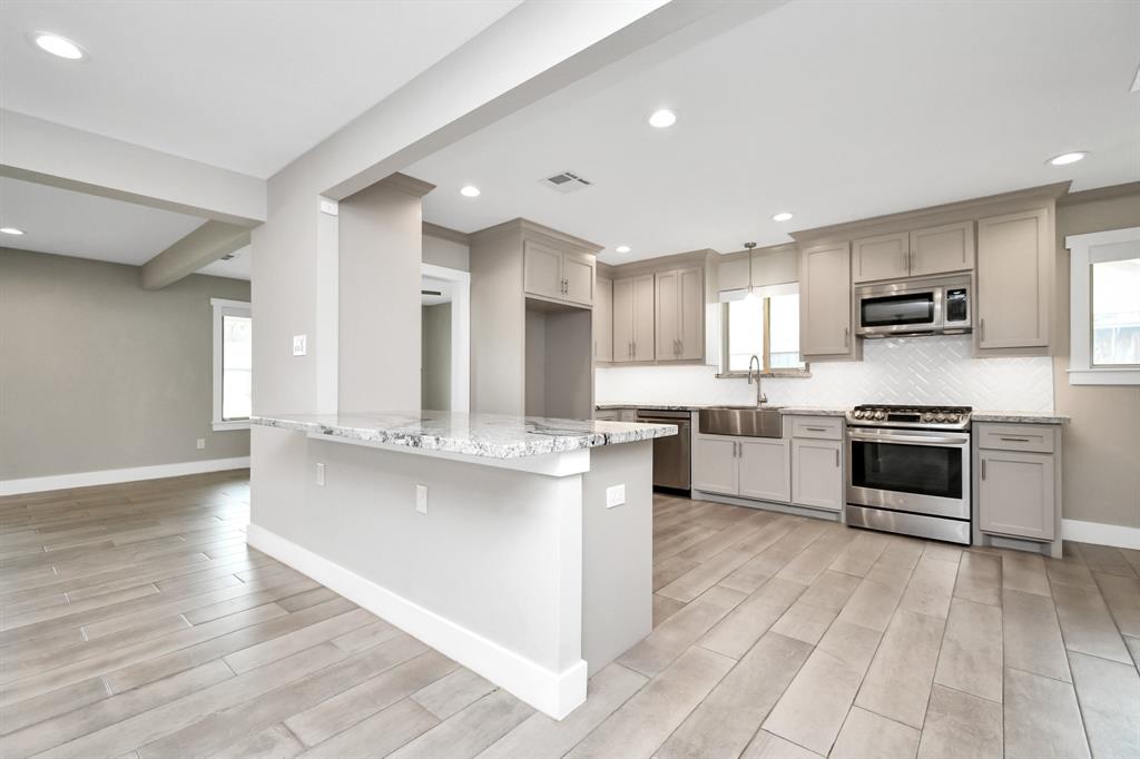 a kitchen with stainless steel appliances kitchen island granite countertop a stove a sink and a refrigerator