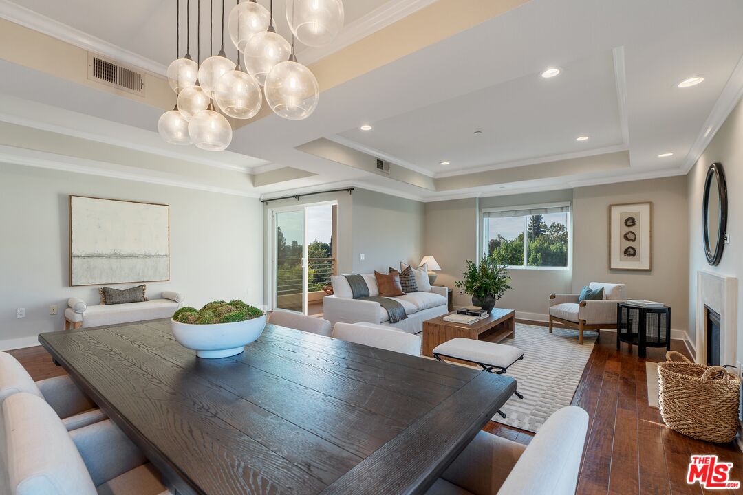 a living room with dining table a large window and potted plants