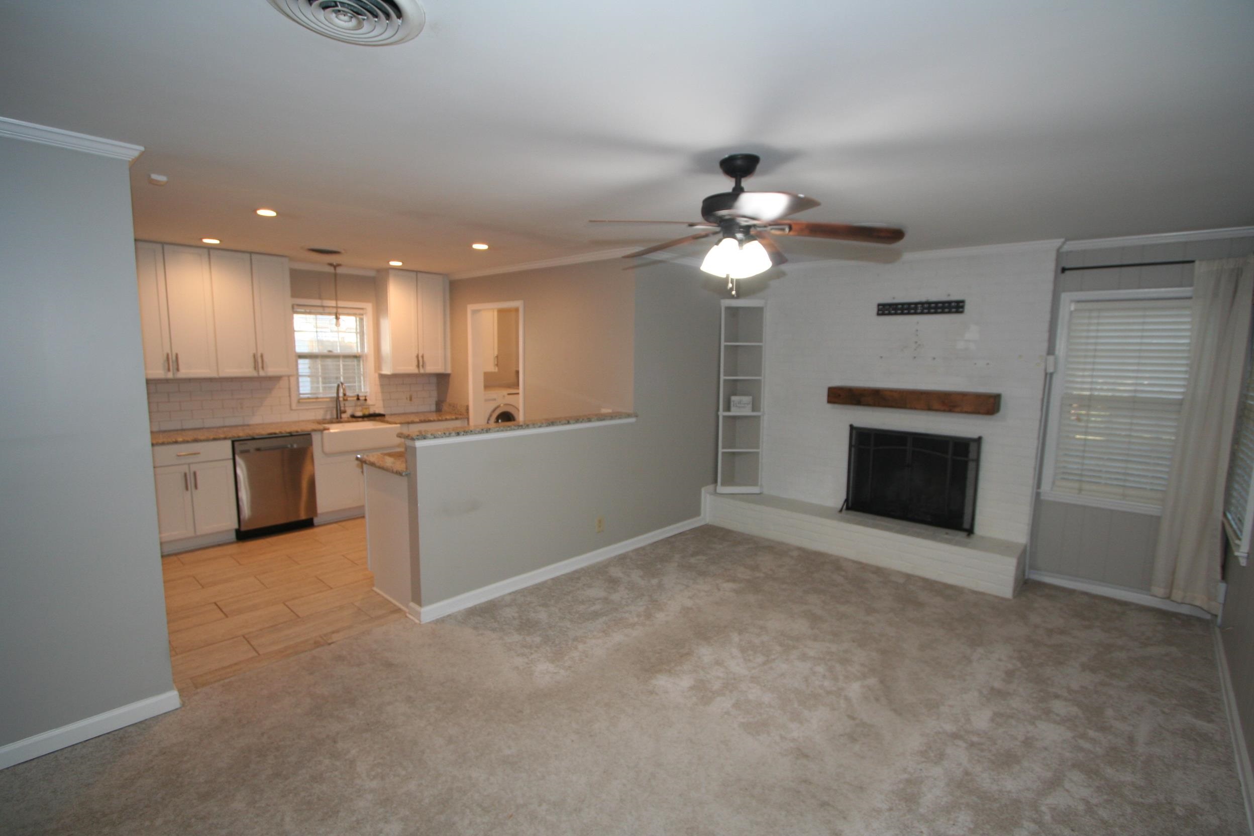 Kitchen featuring white cabinets, stainless steel dishwasher, light carpet, and crown molding