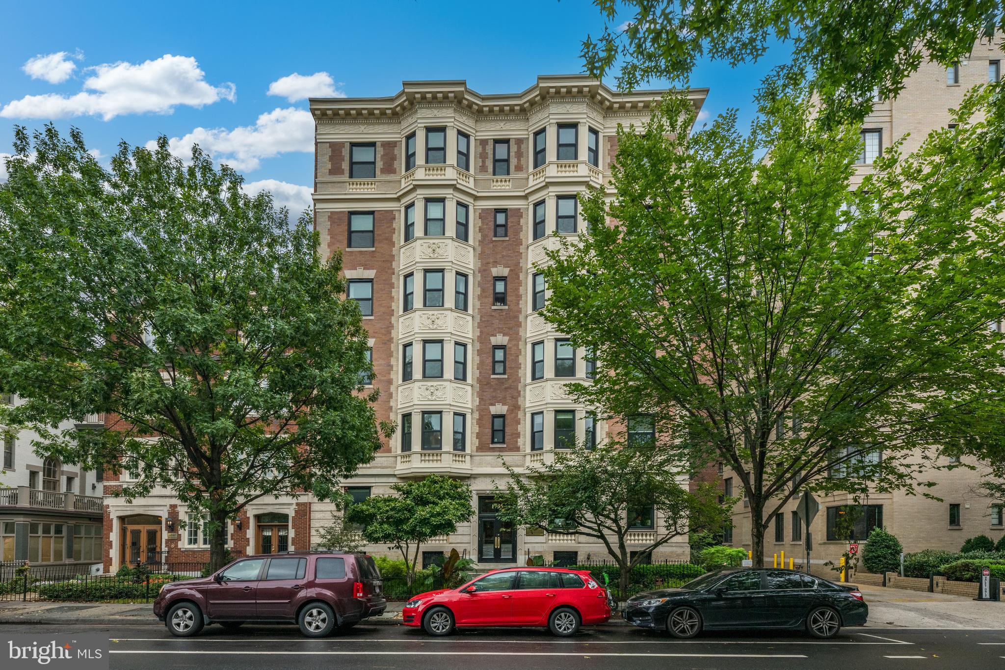 a front view of residential houses with cars parked