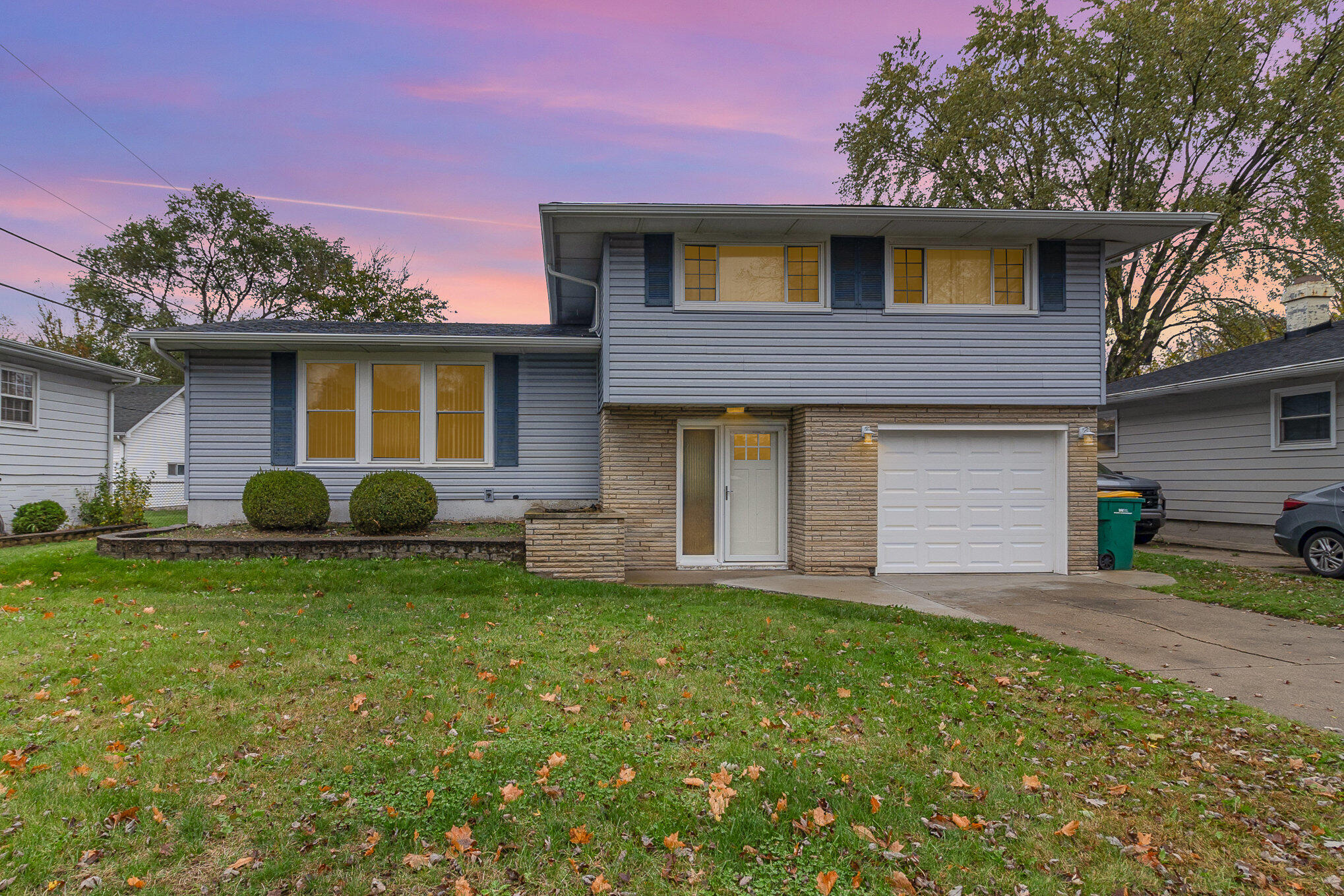 a front view of house with yard and trees in the background