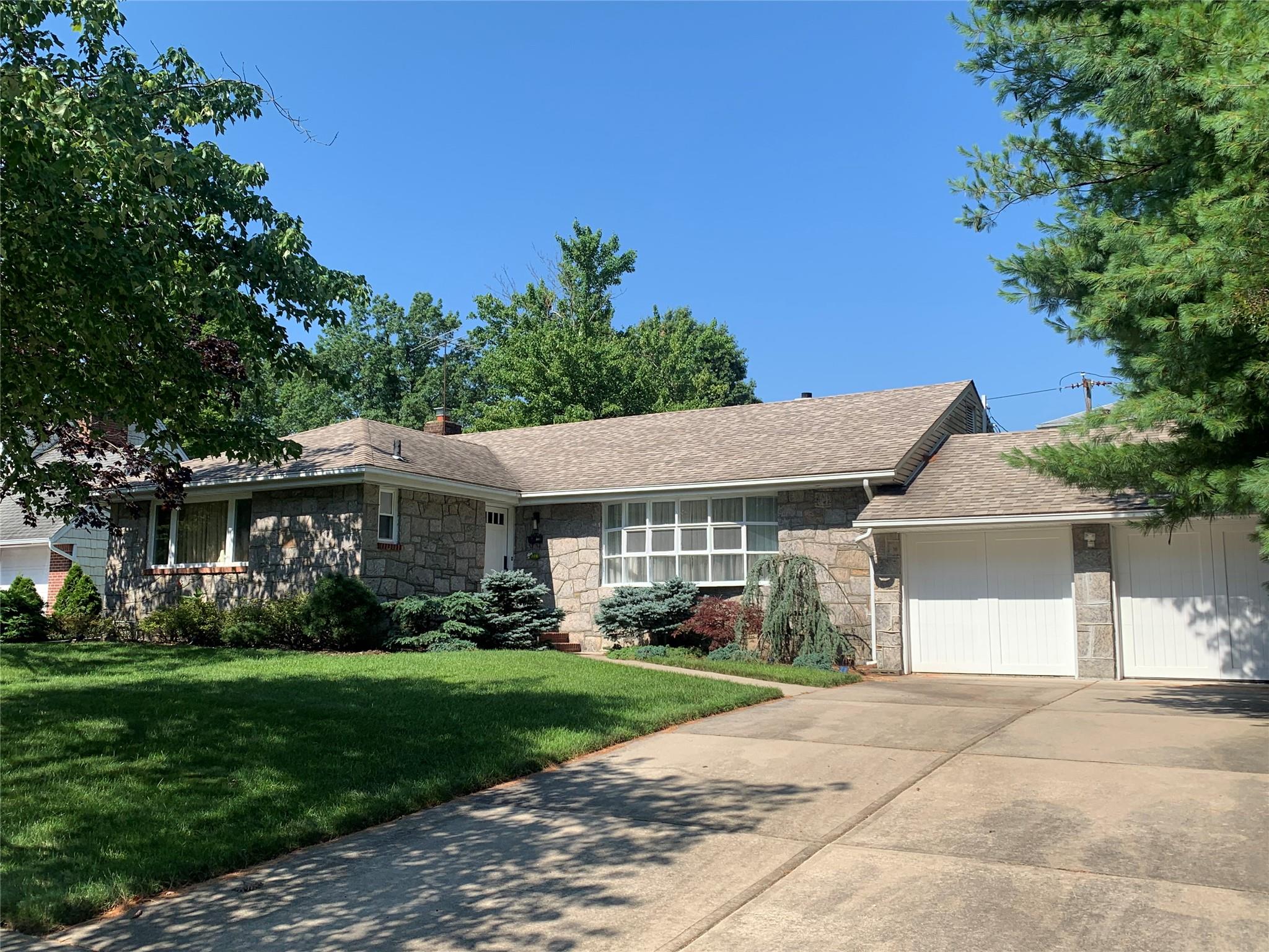 Ranch-style home featuring a garage and a front lawn