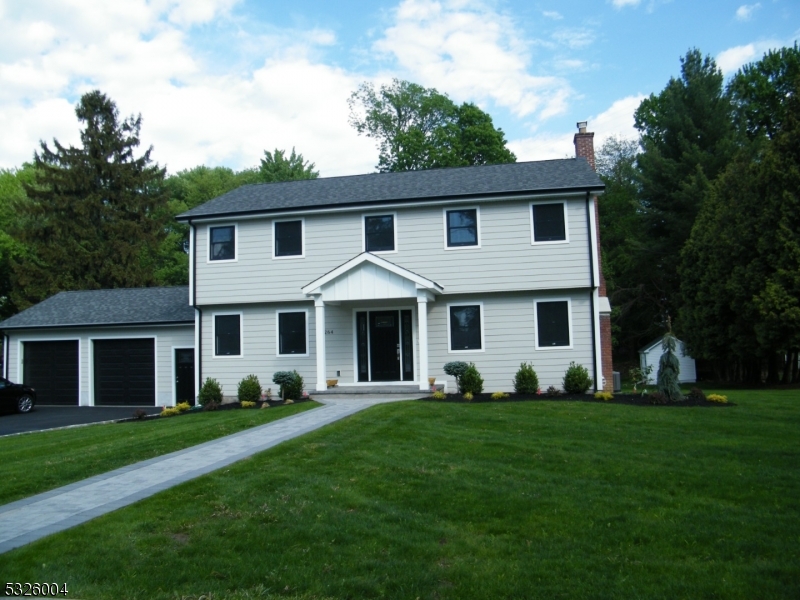 a front view of a house with a garden and trees