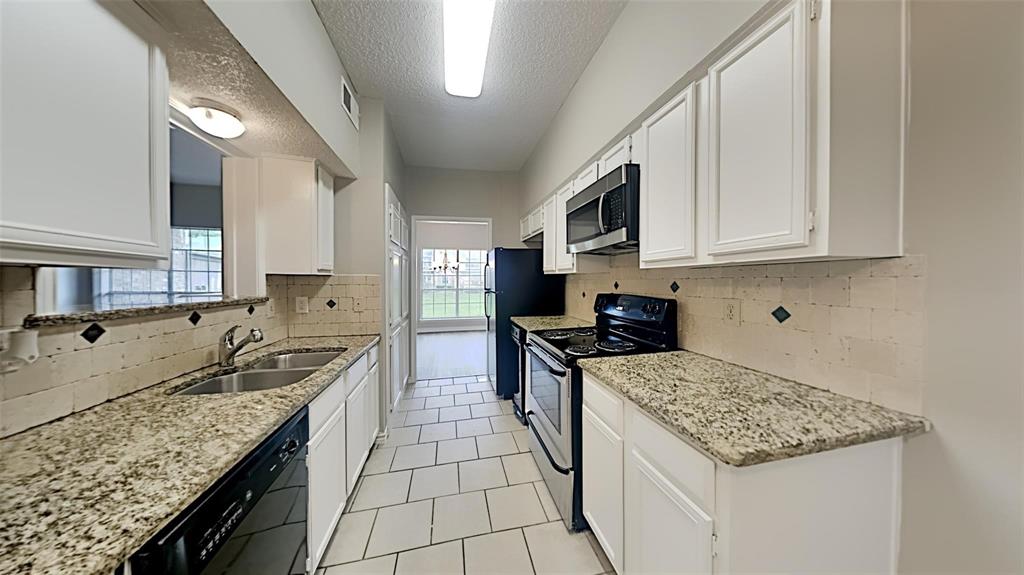 a kitchen with granite countertop a sink a counter top space and cabinets