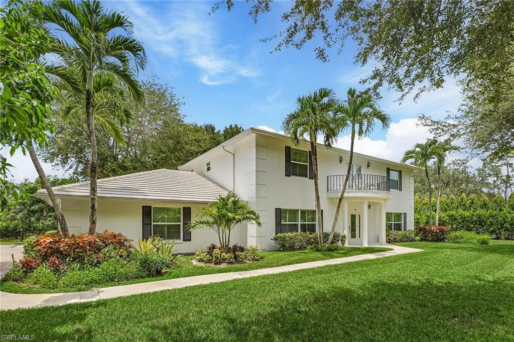 View of front of property with a front yard and a balcony