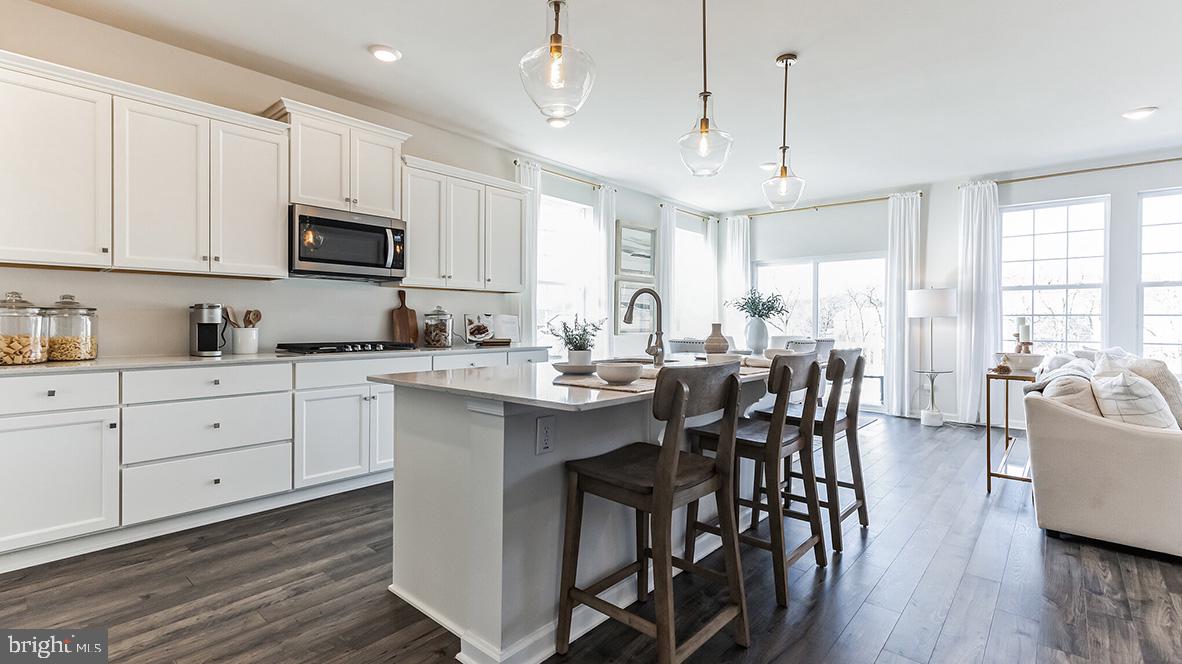 a kitchen with stainless steel appliances kitchen island granite countertop a table chairs microwave and cabinets