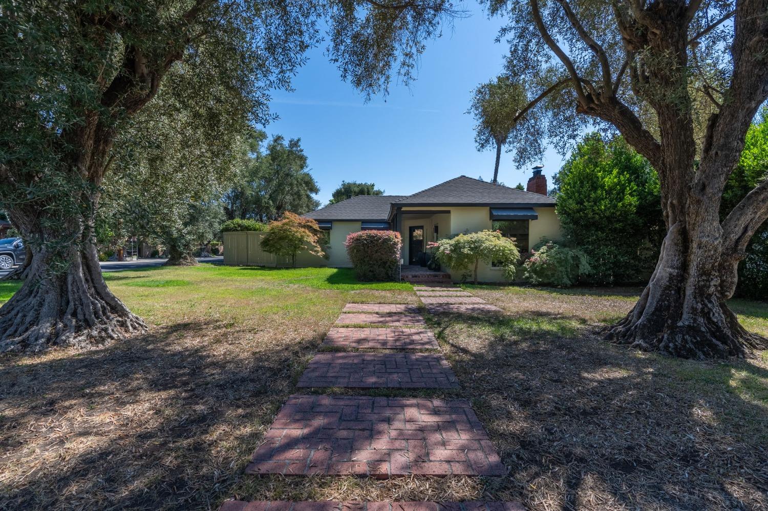 a view of a house with a yard and large trees