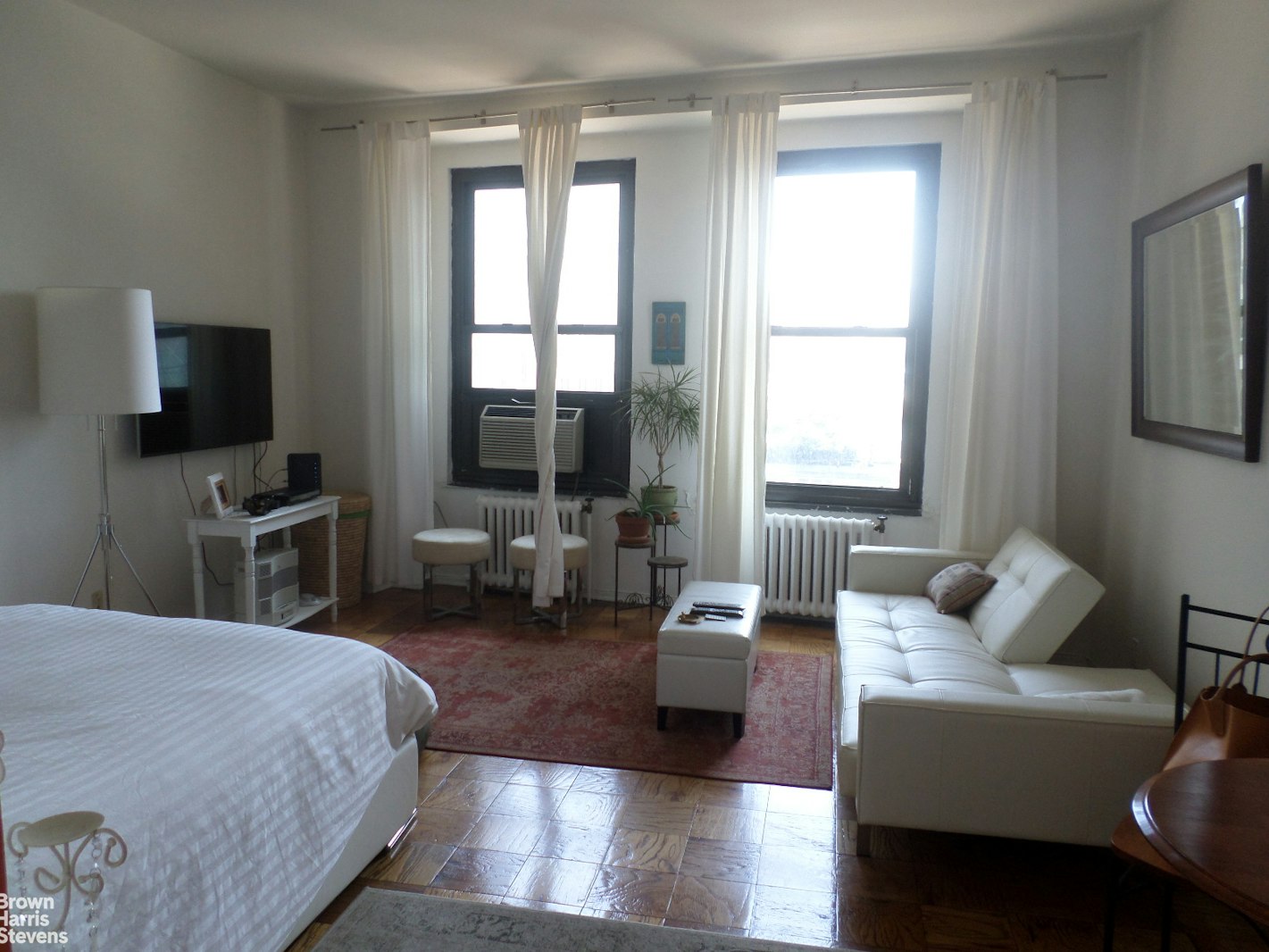 a bedroom with a bed couch and a flat tv screen