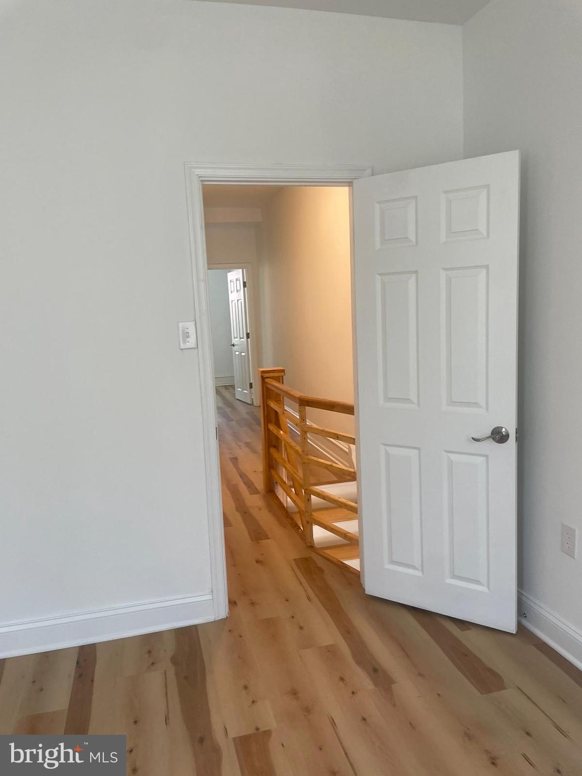 a view of an empty room with wooden floor and a bathroom