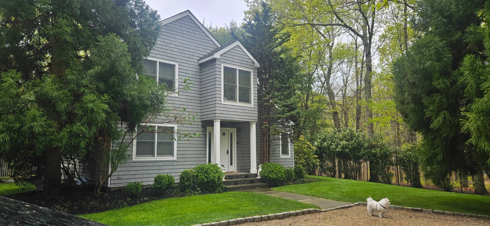 front view of a house with a yard and an trees