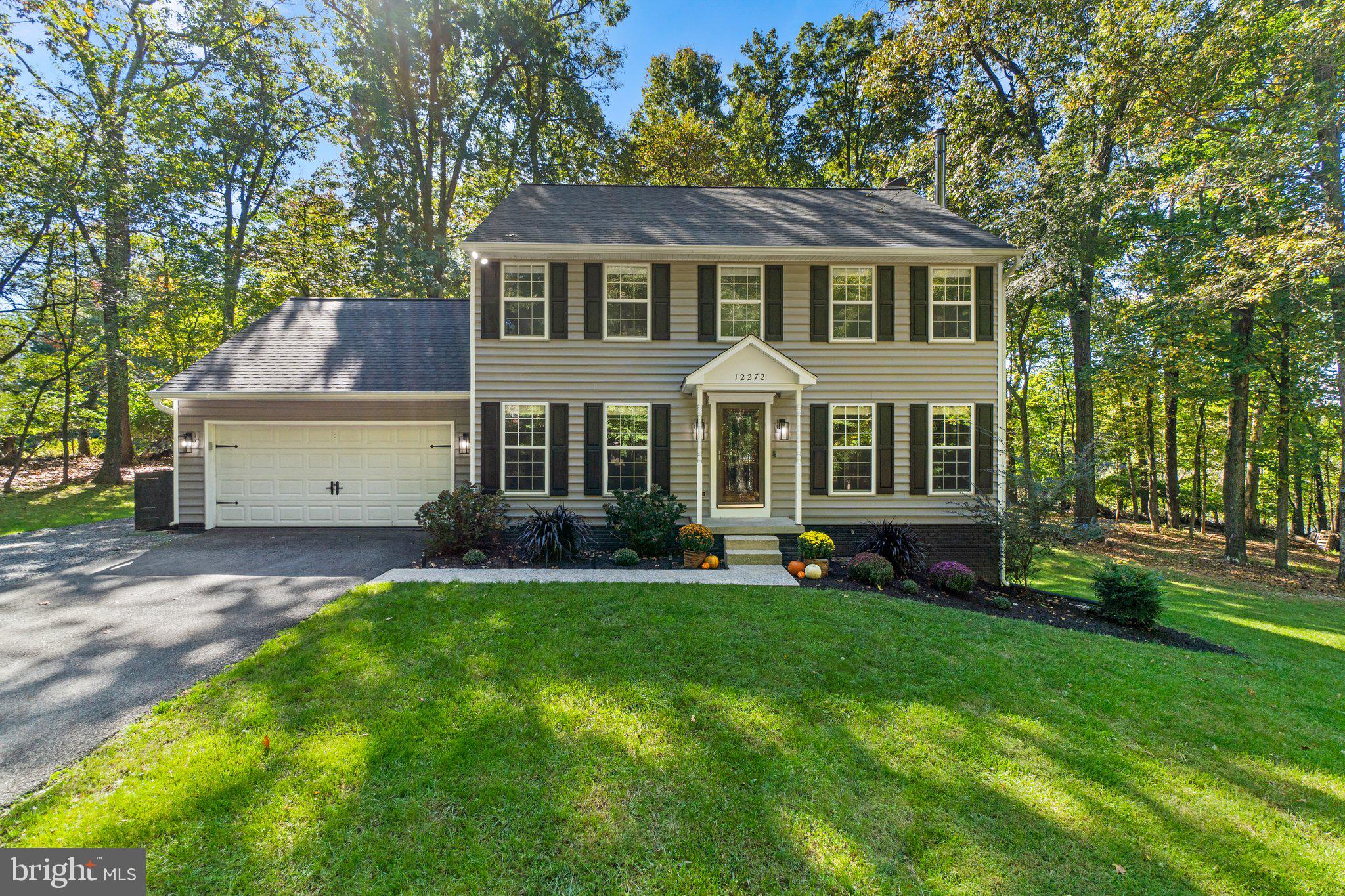 a front view of a house with a garden and trees