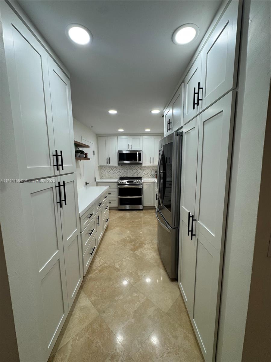 a kitchen with white cabinets and stainless steel appliances