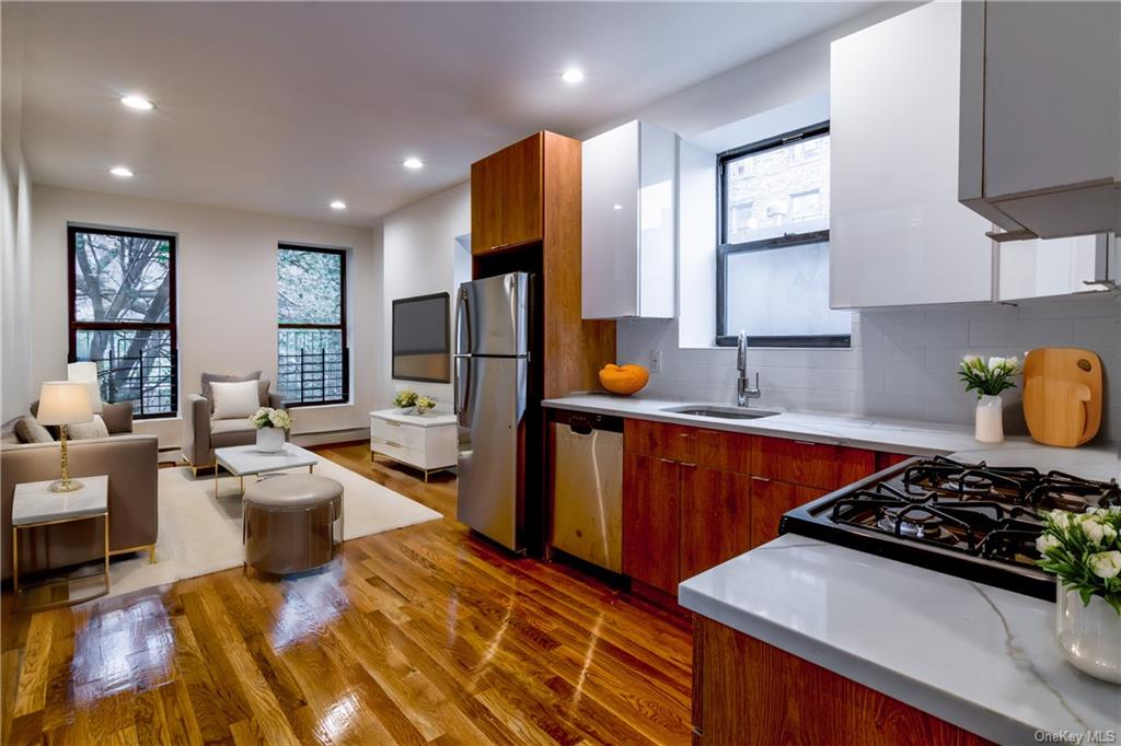 Kitchen with sink, appliances with stainless steel finishes, dark hardwood / wood-style floors, backsplash, and white cabinets