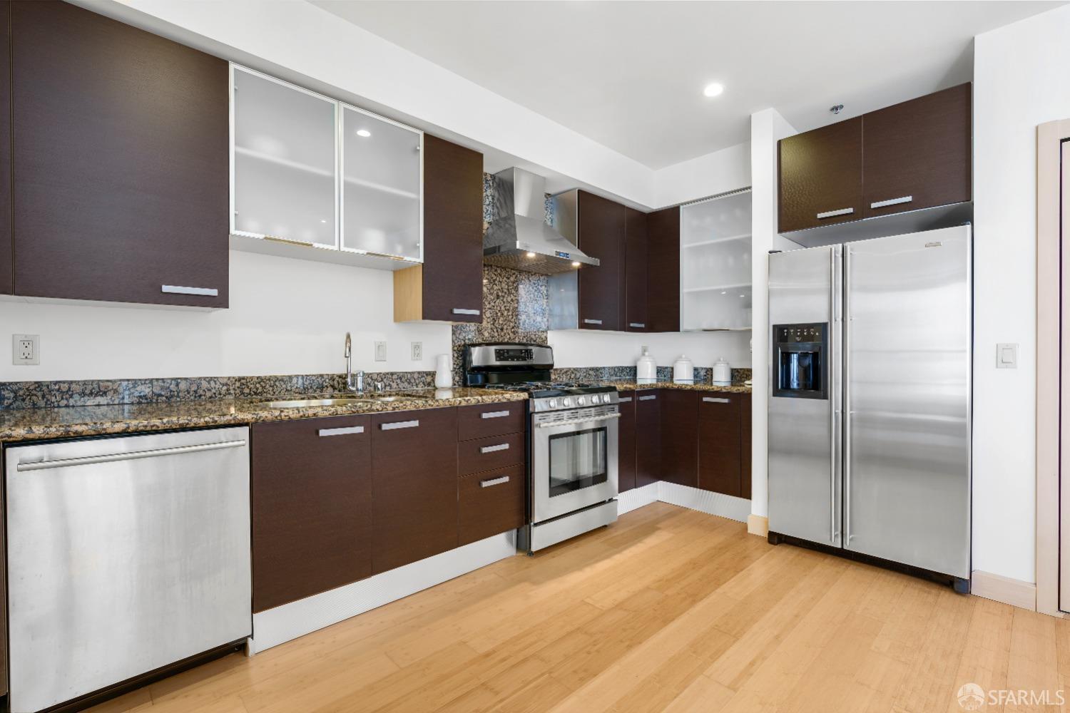 a kitchen with granite countertop a refrigerator stove top oven and sink