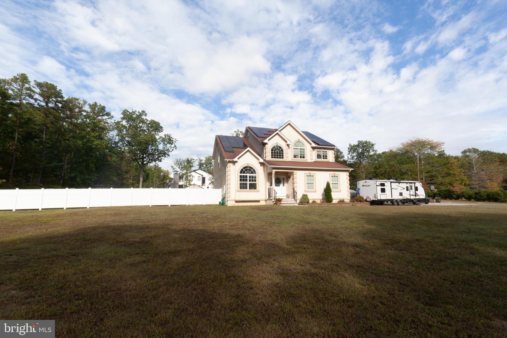 a view of a white house next to a yard with big trees