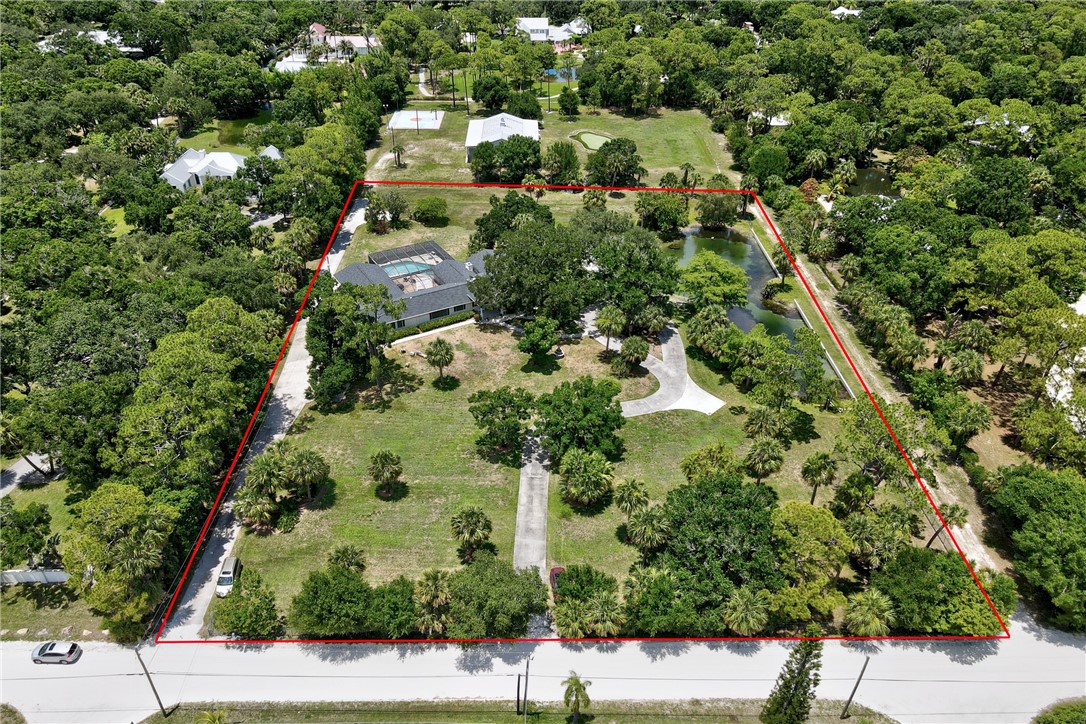 an aerial view of residential house with outdoor space and trees all around