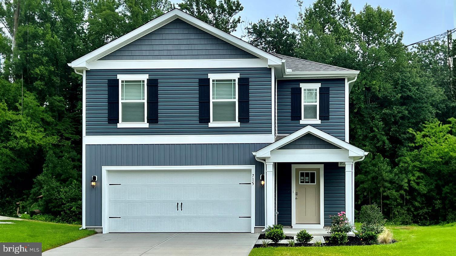 a front view of a house with a yard garage and trees