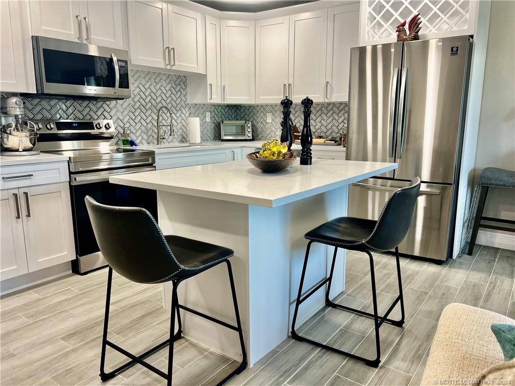 a kitchen with stainless steel appliances a dining table chairs refrigerator and sink