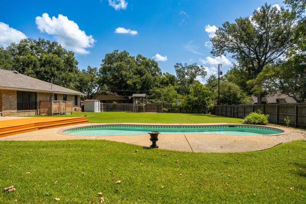 a view of pool with umbrella and trees in the background