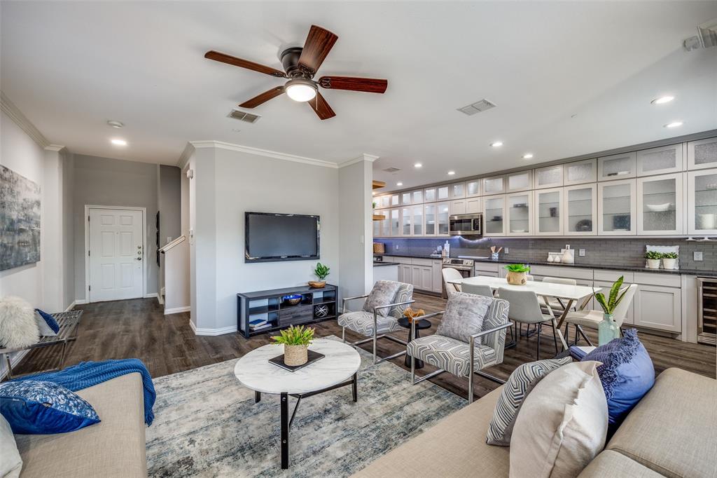 a living room with furniture kitchen view and a wooden floor