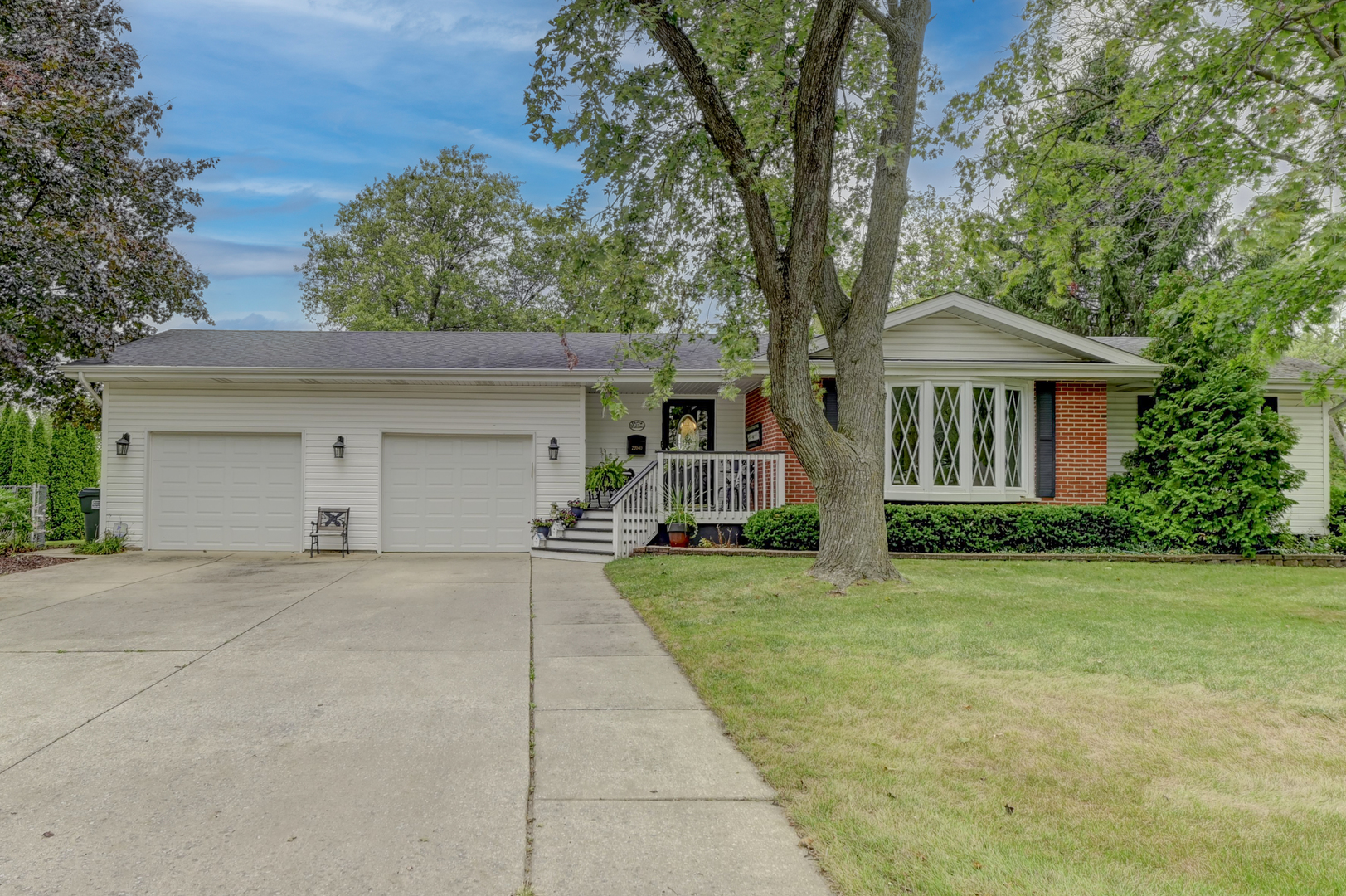 a front view of a house with a garden and trees