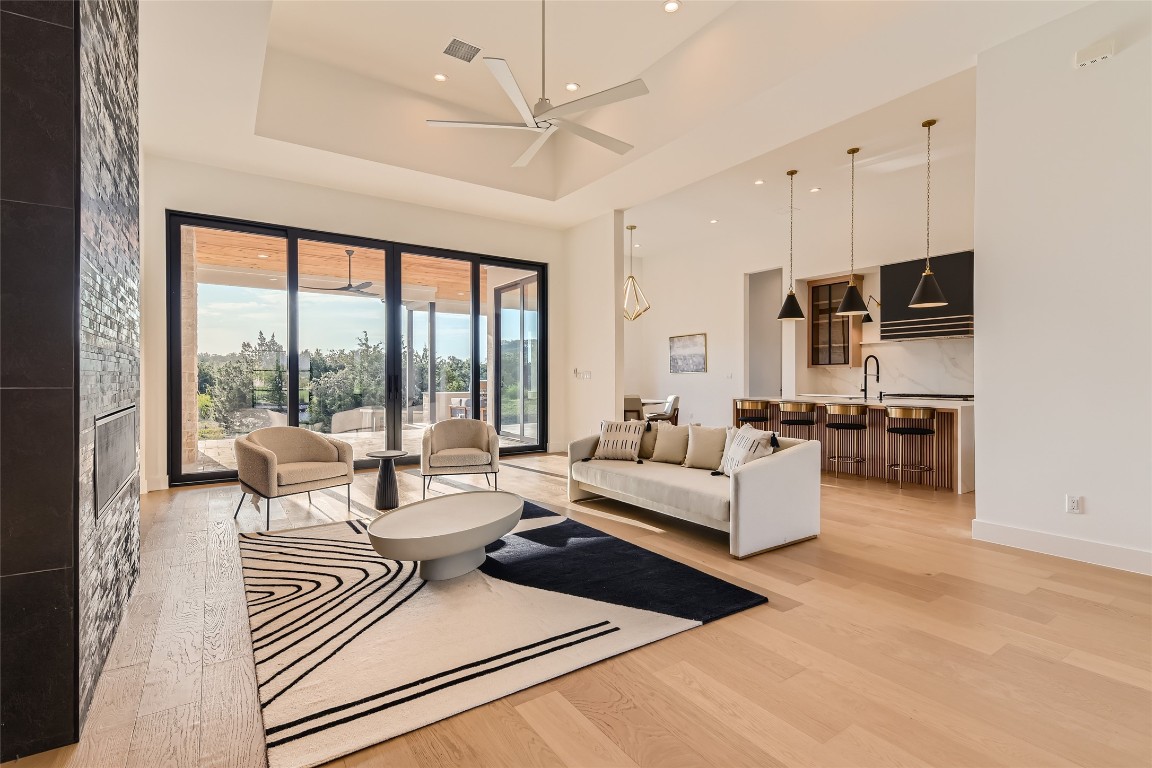 a living room with furniture and a large window with kitchen view