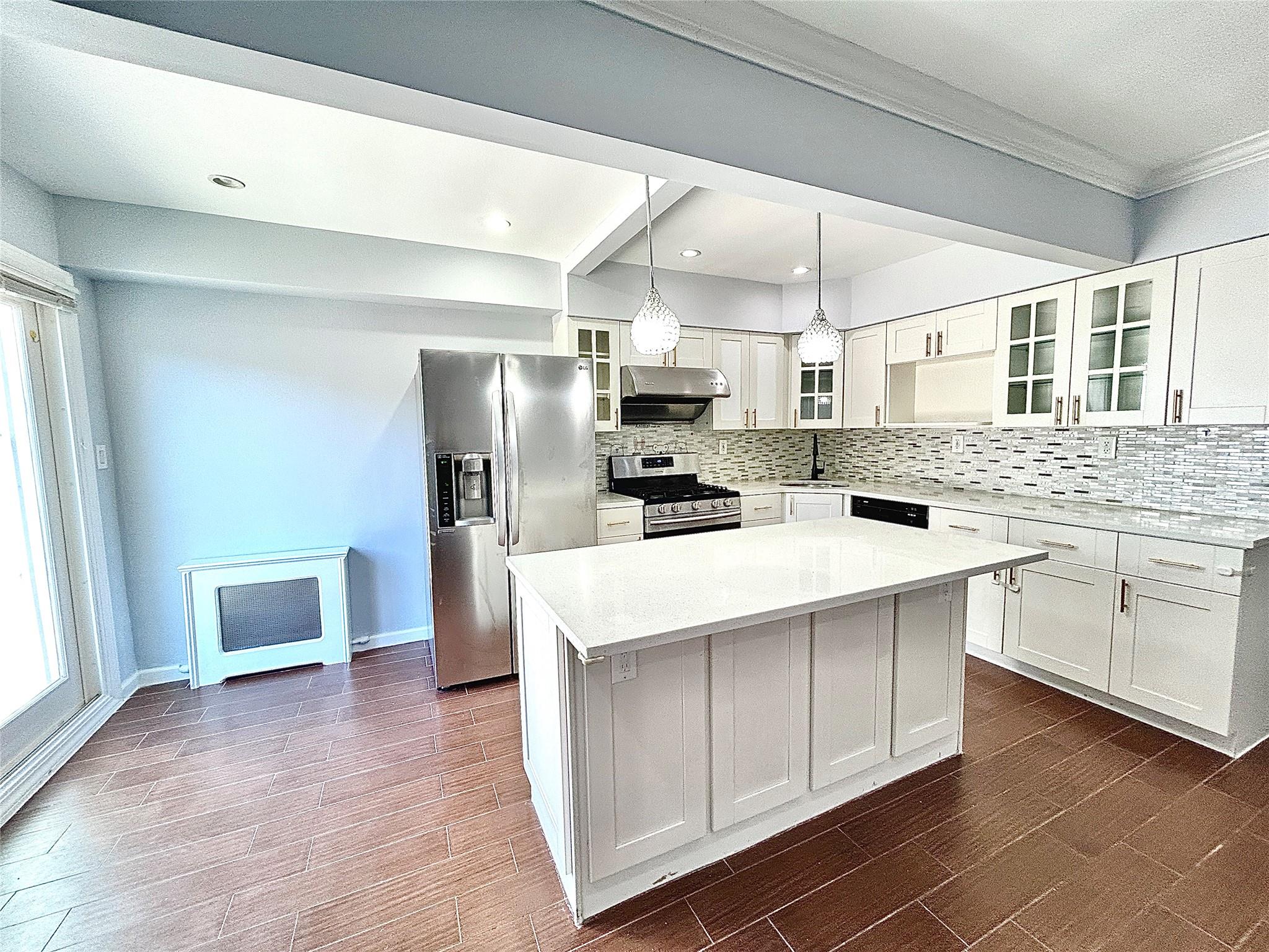 Kitchen with appliances with stainless steel finishes, white cabinetry, a kitchen island, and sink