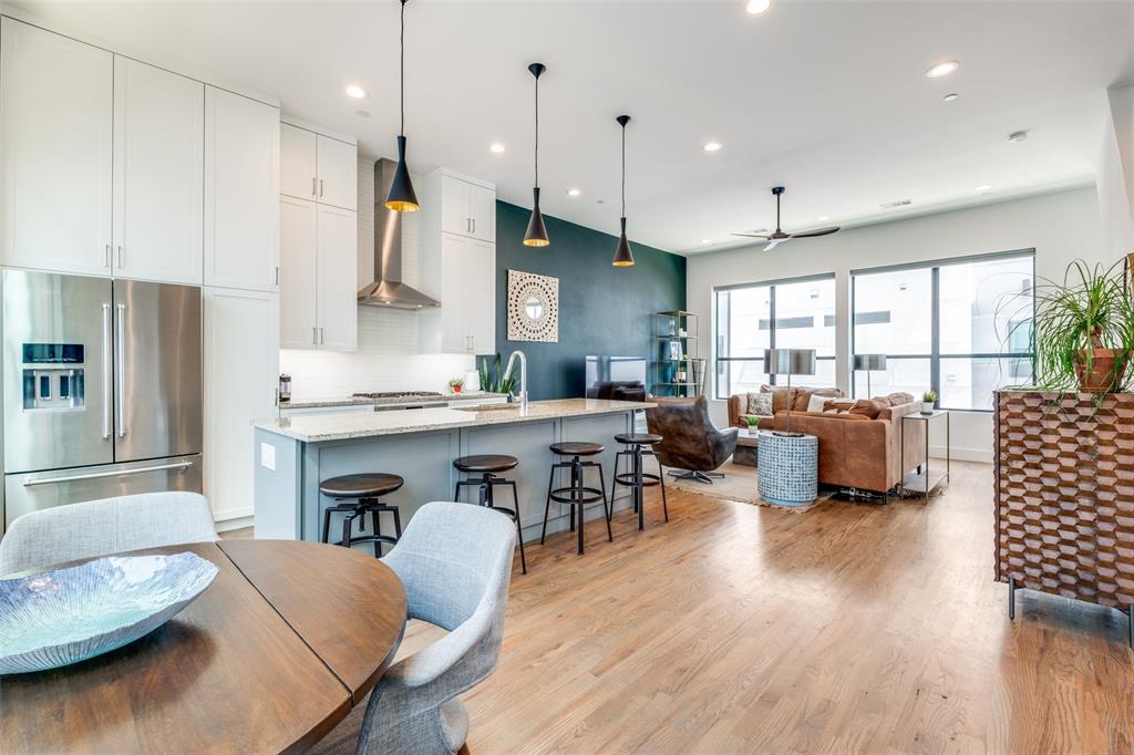 a living room with furniture kitchen area and a wooden floor