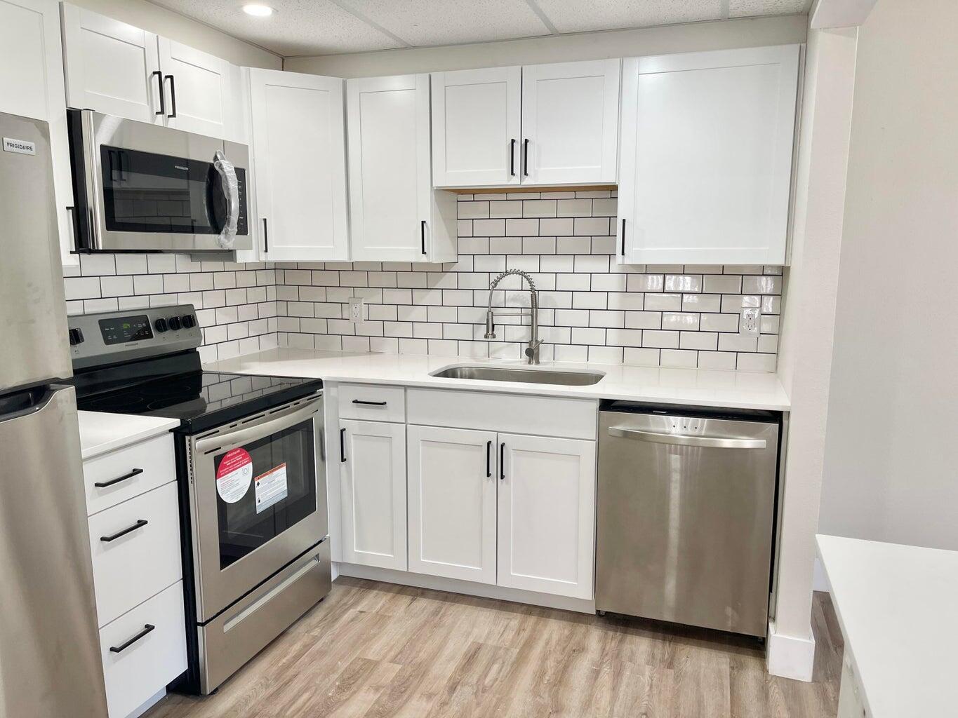 a kitchen with stainless steel appliances white cabinets and white appliances