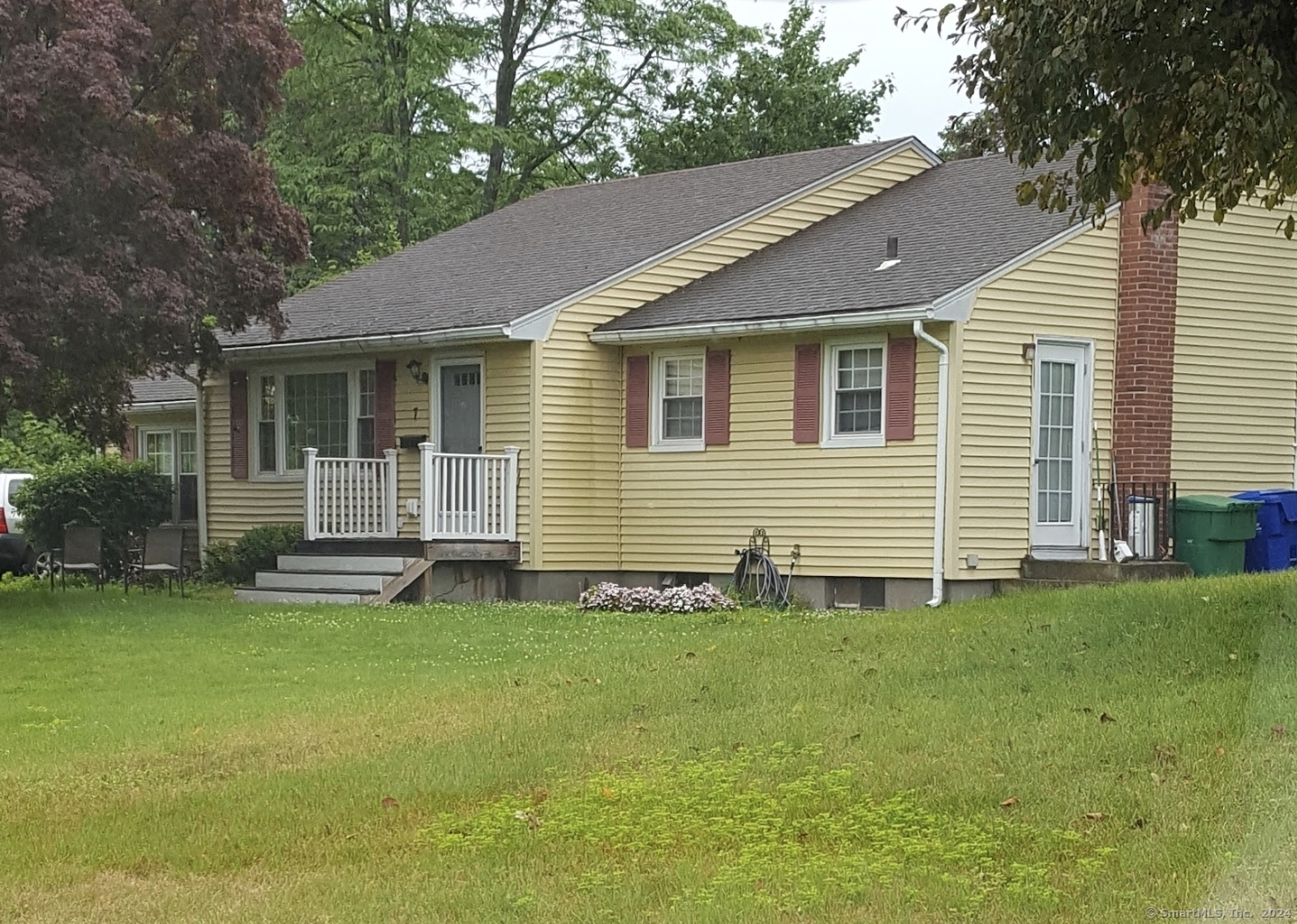 a backyard of a house with lawn chairs and a large tree