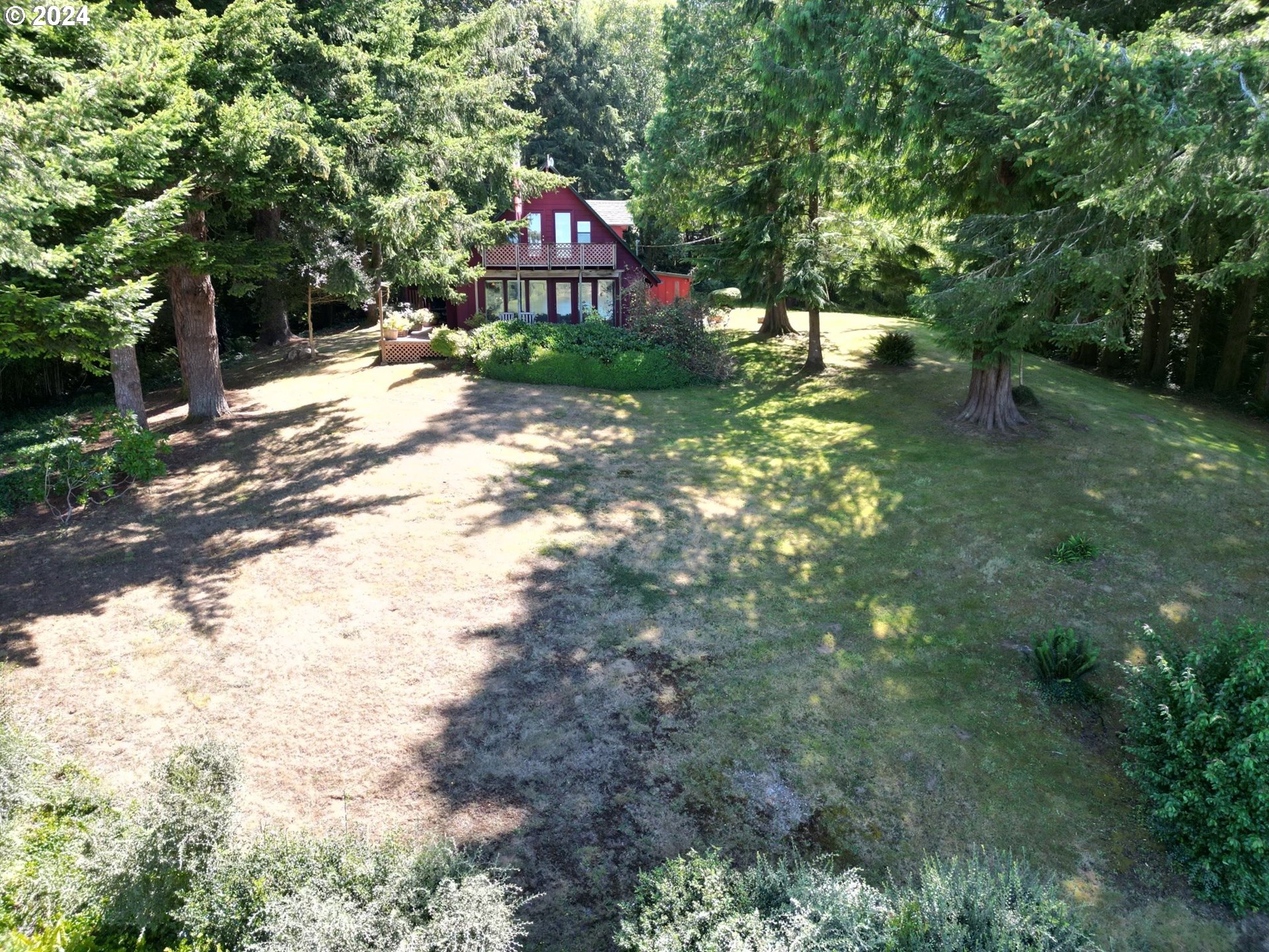 a view of a wooden house with a yard and large trees