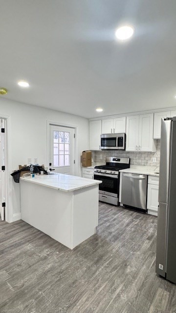 a kitchen with stainless steel appliances a sink a stove a refrigerator cabinets and a window