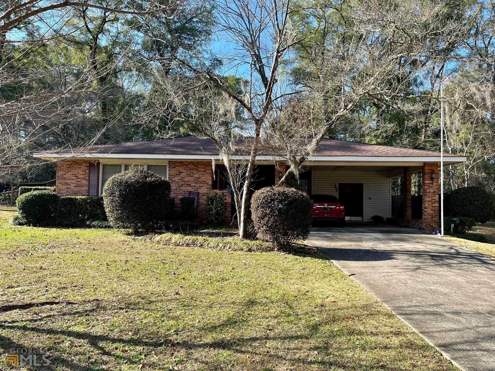 a view of a house with potted plants and large trees