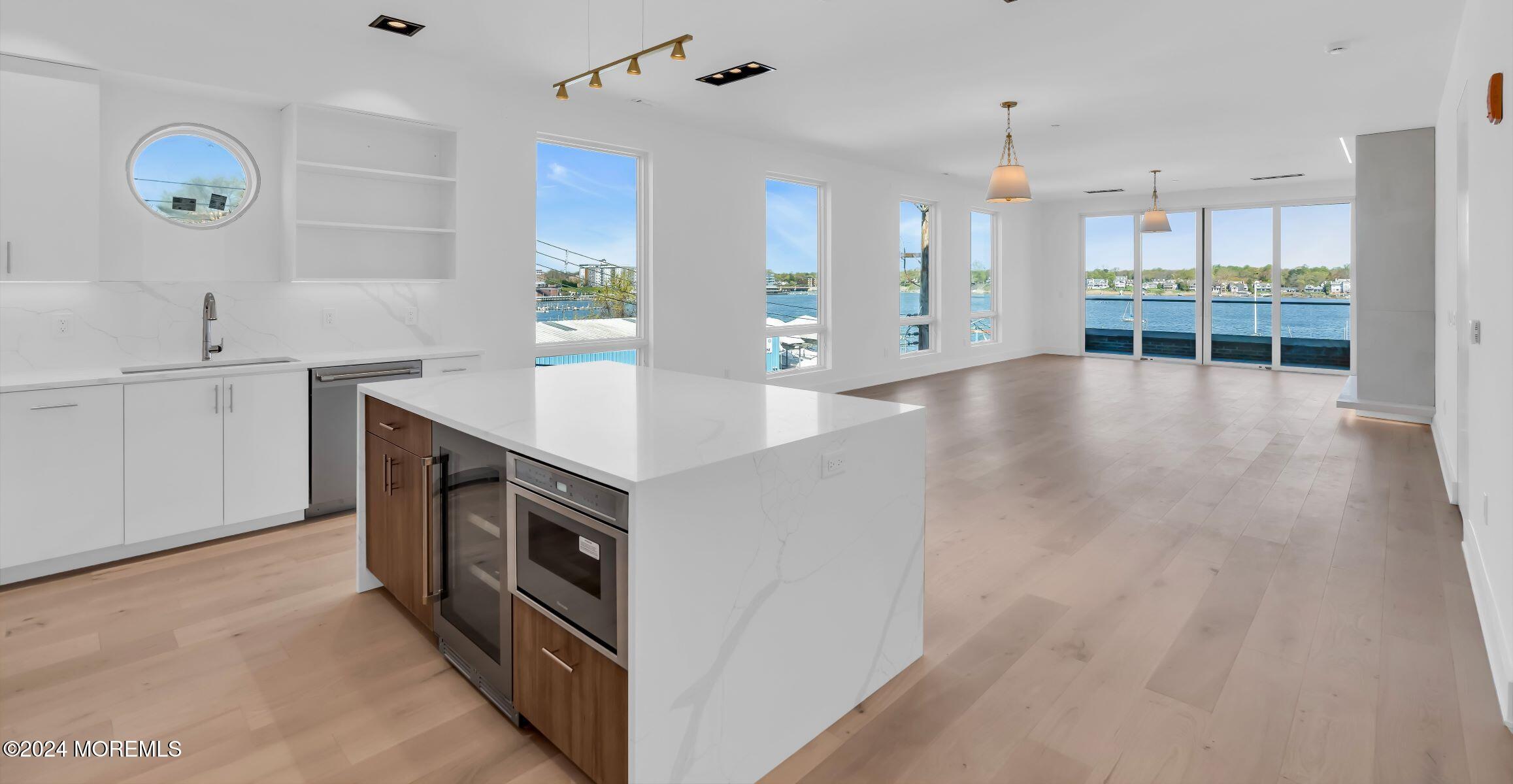 a view of a kitchen with kitchen island a stove a refrigerator a sink and a counter top space