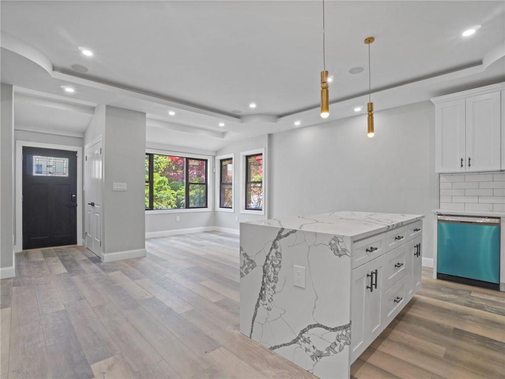 Kitchen with white cabinetry, dishwasher, and light hardwood / wood-style flooring