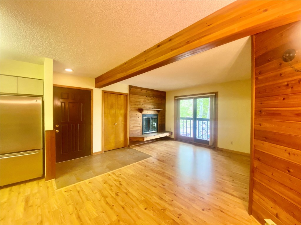 a view of a hallway with wooden floor and a refrigerator