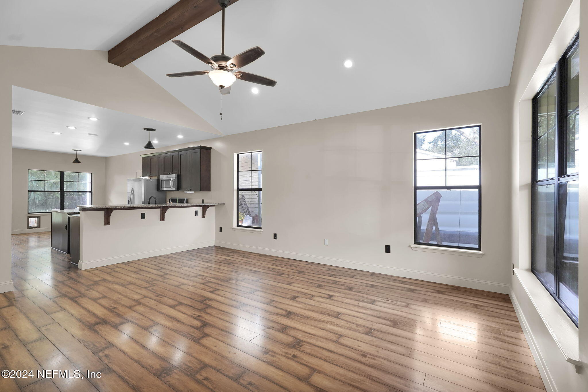 a view of a kitchen with a kitchen island wooden floor and a ceiling fan