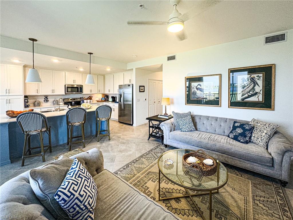 a living room with furniture kitchen view and a chandelier